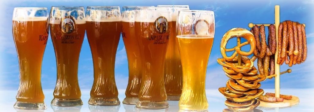 Eine typische Bier-Szene mit sieben großen, biergefüllten Gläsern, Brezeln und Würsten.